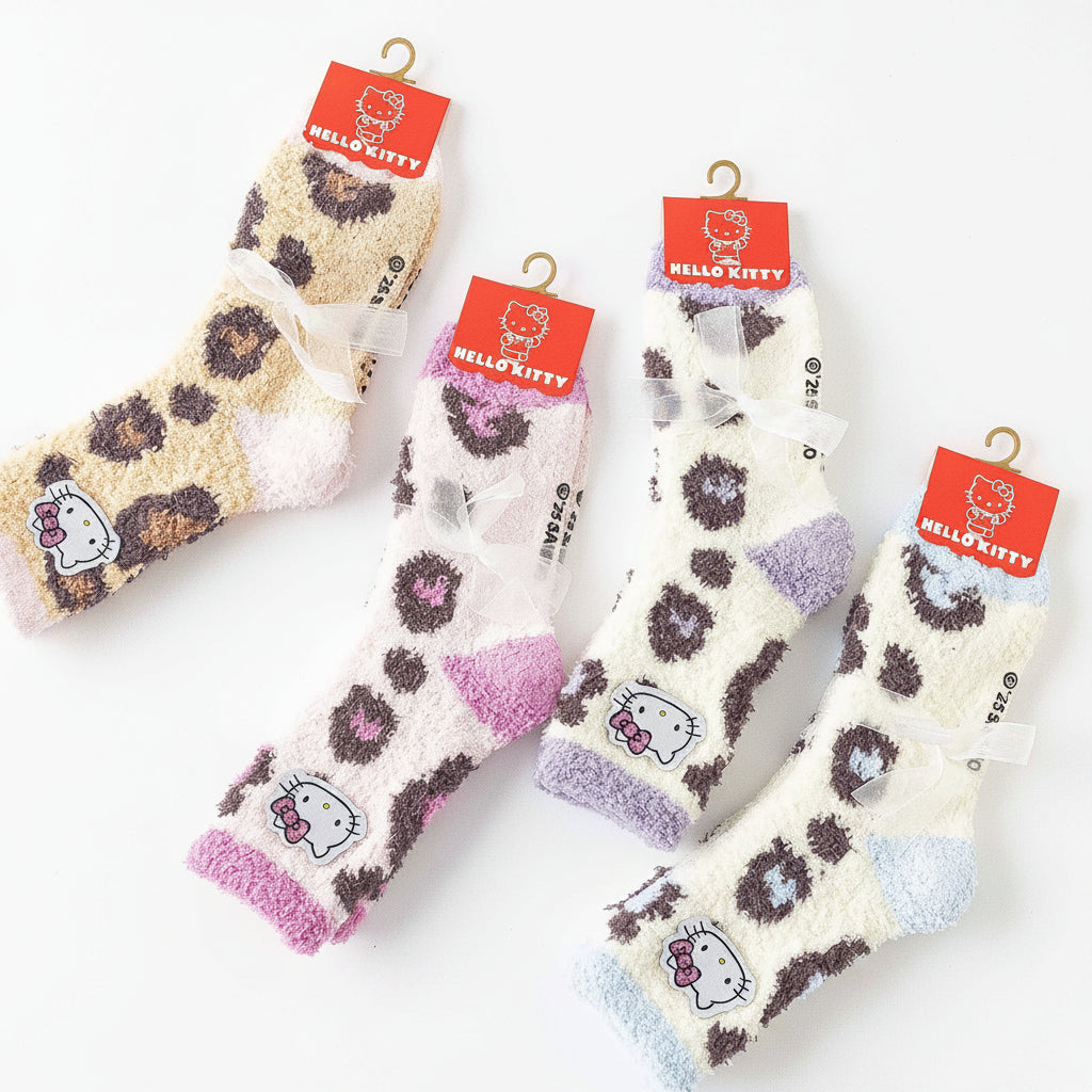 Four pairs of fuzzy Hello Kitty socks with leopard print patterns in different colorways, hanging from red Hello Kitty tags on a white background. Text at the bottom reads 'Sanrio Characters'.