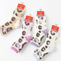 Four pairs of fuzzy Hello Kitty socks with leopard print patterns in different colorways, hanging from red Hello Kitty tags on a white background. Text at the bottom reads 'Sanrio Characters'.