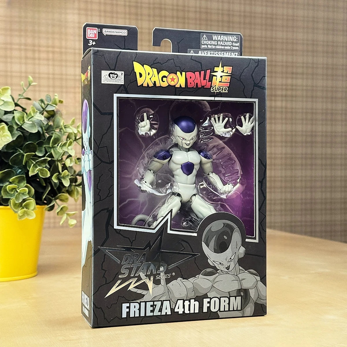 Dragon Ball Z Super Frieza 4th Form action figure packaging on a wooden surface with a plant in the background.